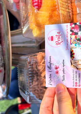 hand holding business card for Rosita bakery in front of boxed individual cakes