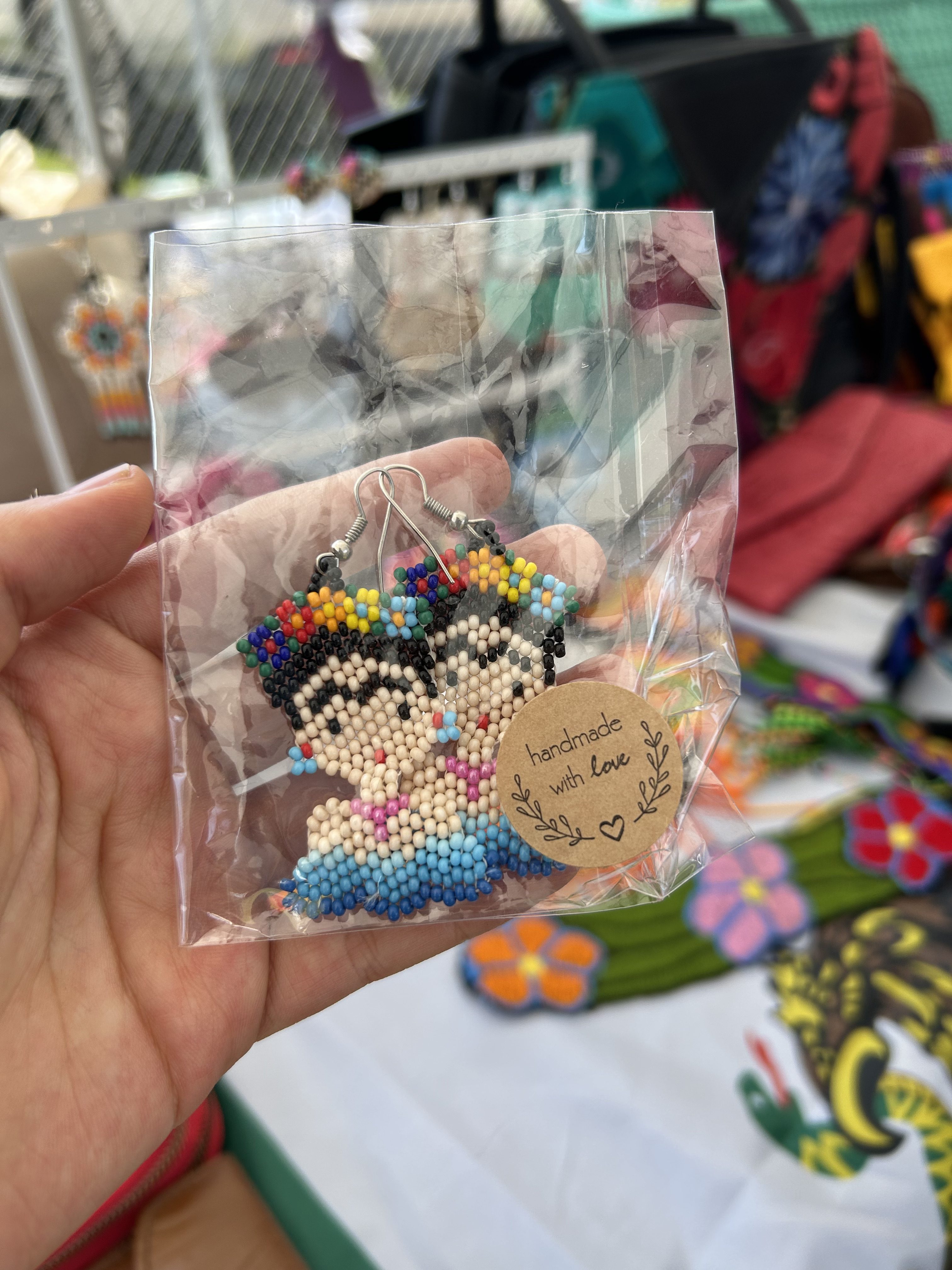 hand holding a pear of handmade Frida Kahlo bead earrings