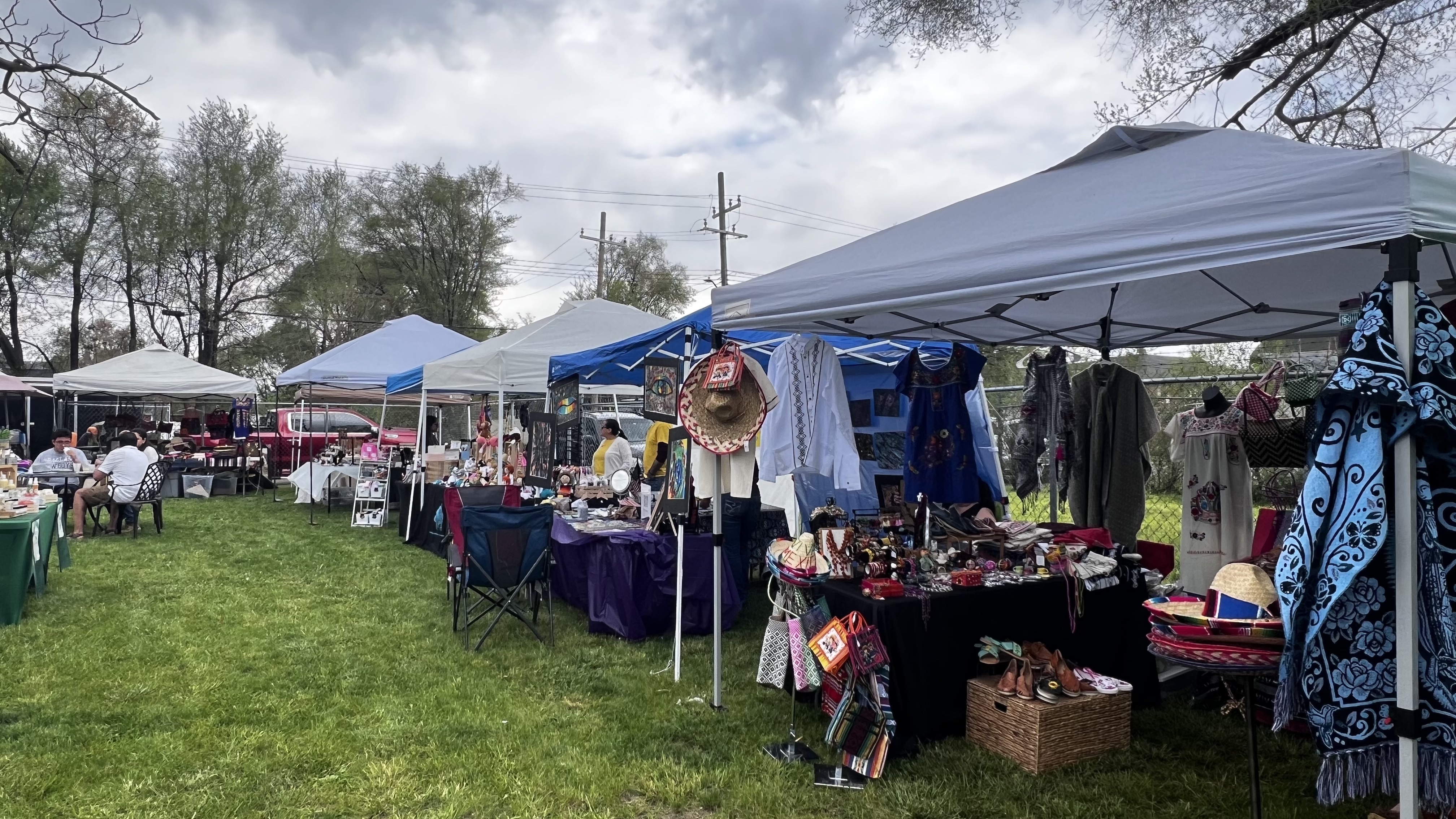 Event with multiple tents showcasing clothes, crafts, and accessories from small businesses.