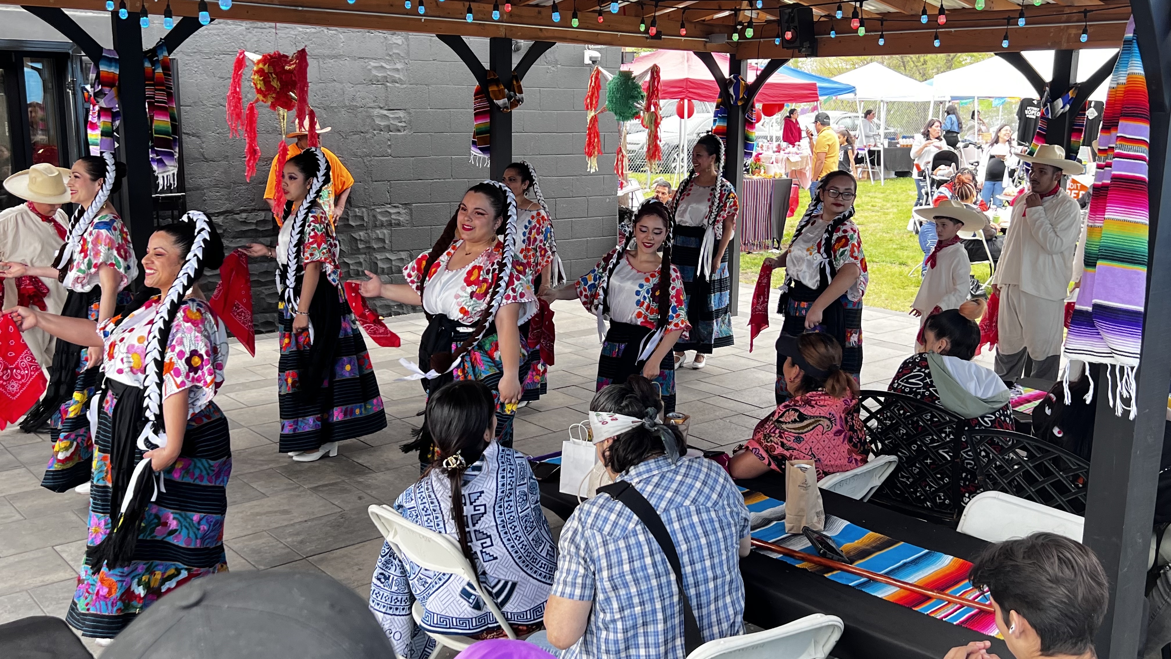 A vibrant event of people dressed in traditional Mexican attire, engaging in a dance celebration.